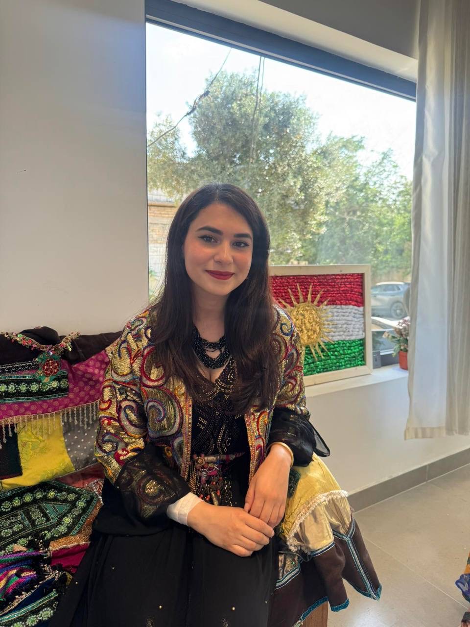 Lana Peshraw at her exhibition, beside her Kurdish flag artwork