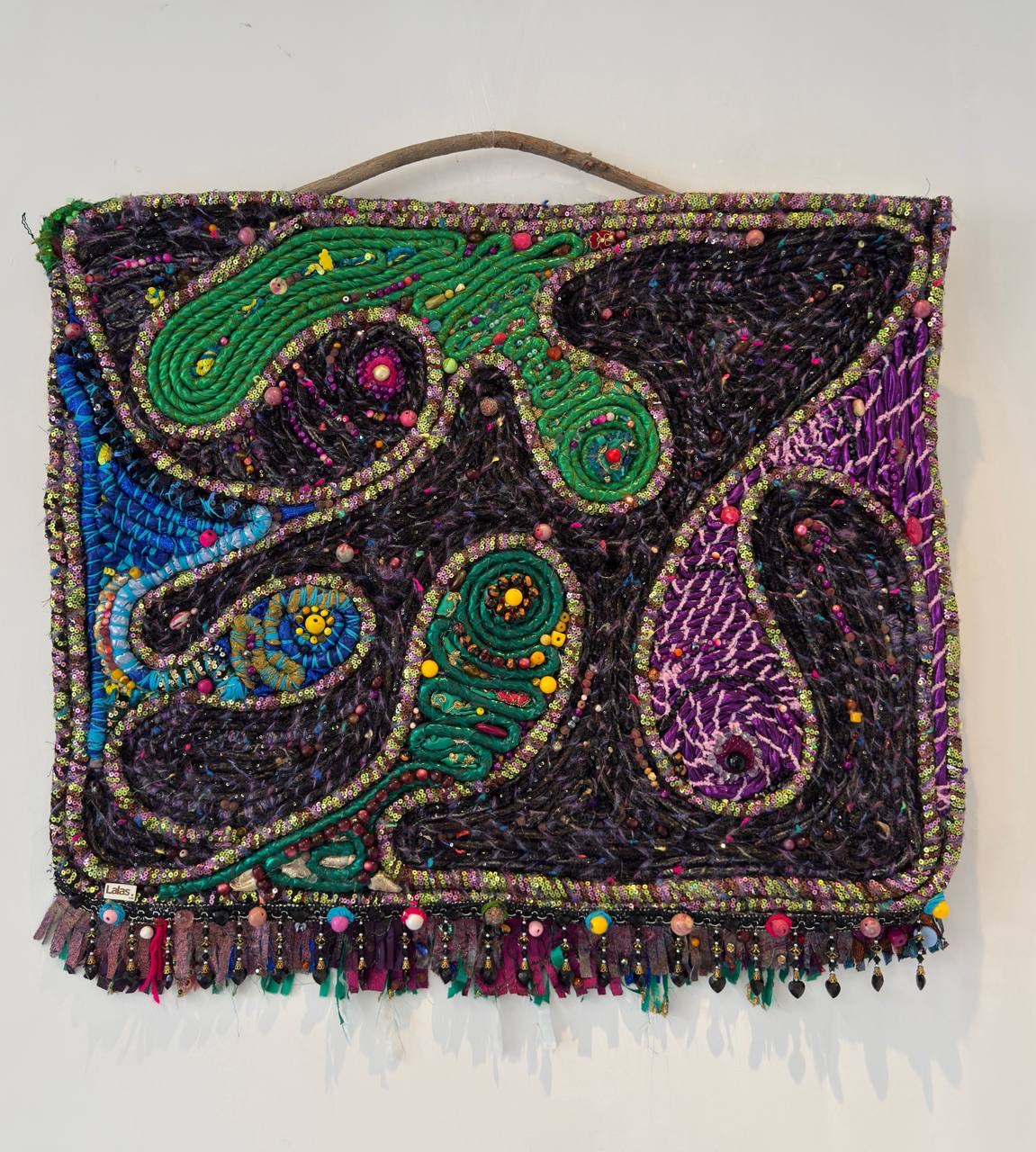 Wall rug with green, blue and purple paisley shapes on a driftwood hanger